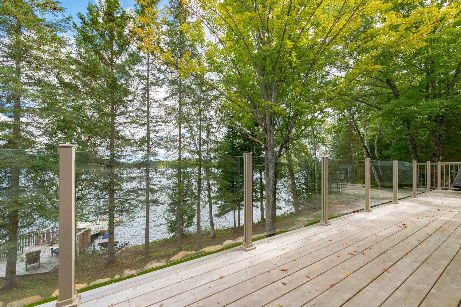 Topless glass railing along a forested lakeside deck