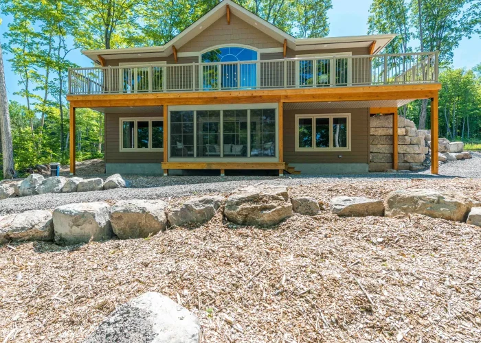 Three-season room enclosed beneath a raised deck on a wooded property