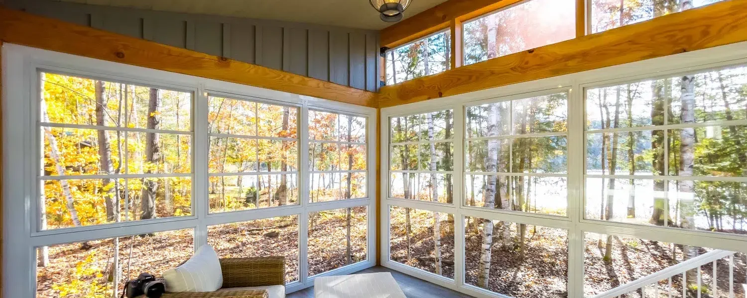 White-framed ViewFlex windows surrounding a bright three-season porch in autumn